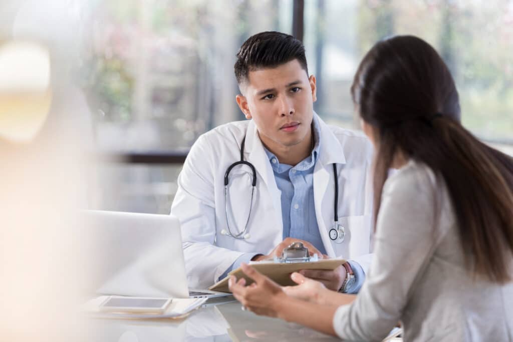 Serious male doctor talks with female patient
